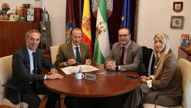 Momento de la firma del acuerdo en Chiclana con el alcalde y los responsables sentados en la mesa de despacho de madera.