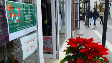 Planta de la Navidad junto al escaparate de un comercio que hace descuentos en Rota.