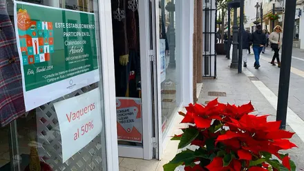 Planta de la Navidad junto al escaparate de un comercio que hace descuentos en Rota.
