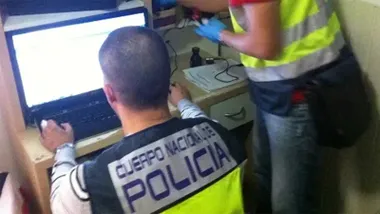 Imagen de archivo de agentes del Grupo de Delitos Tecnológicos de la Policía Nacional, trabajando frente a equipos informáticos en dependencias policiales. En primer plano se aprecia el escudo corporativo de la Policía y pantallas con análisis de datos, representando la labor digital de rastreo de delitos informáticos.