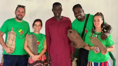 Cinco personas posan sonrientes frente al terreno en construcción del futuro colegio de Louga, en Senegal. En la derecha, Ana Domínguez y su marido, Bibi Faye, aparecen junto a los voluntarios gaditanos Elda Folgar y Manolo Ons, y a un colaborador local del proyecto.