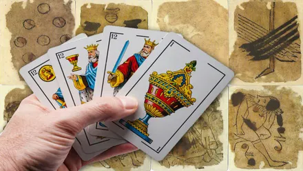 Mano sosteniendo unas cartas modernas y de fondo la baraja española de 1390