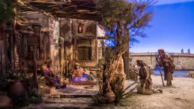 Portal de Belén con figuras y fondo azulado.