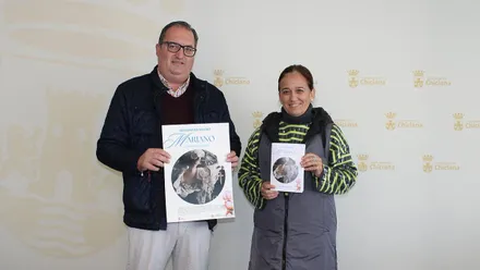 Presentación del Besamanos Magno, dos personas sostienen el cartel en las manos.