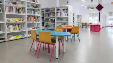 Biblioteca infantil en Rota con sillas de colores y mobiliario blanco.