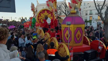 Carroza de la Cabalgata de Reyes Mago de Chiclana en color dorado, hay mucho público viendo el desfile.