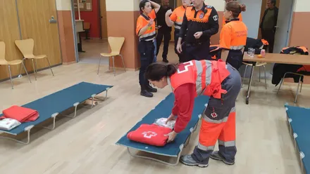 Chica de la Cruz Roja poniendo una manta sobre una cama eventual tipo camilla.