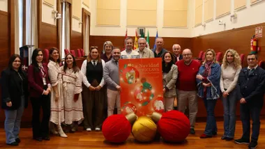 Personas, entre autores, responsables y autoridades en torno al cartel de la Navidad en Chiclana, con tonos rojos.