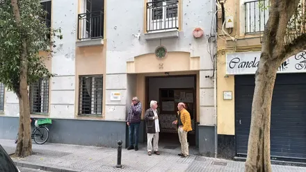 Fotografía tomada frente a la sede de la UDP en la calle de la Rosa, mostrando a varios mayores en la puerta de la instalación del barrio de La Viña.