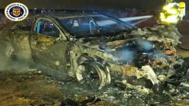 Coche calcinado junto a un bombero.