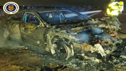 Coche calcinado junto a un bombero.