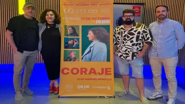 Director y equipo junto al cartel de "Coraje" en tonos anaranjados.