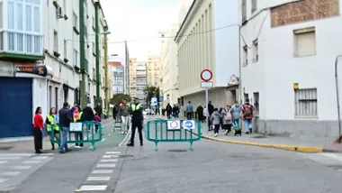 Fotografía tomada en la calle Trille durante la entrada del alumnado al Rebaño de María, mostrando las vallas de restricción, señales de tráfico y la patrulla escolar colaborando con agentes de la Policía Local. En el fondo, se aprecia la fachada del colegio y familias acompañando a los menores.