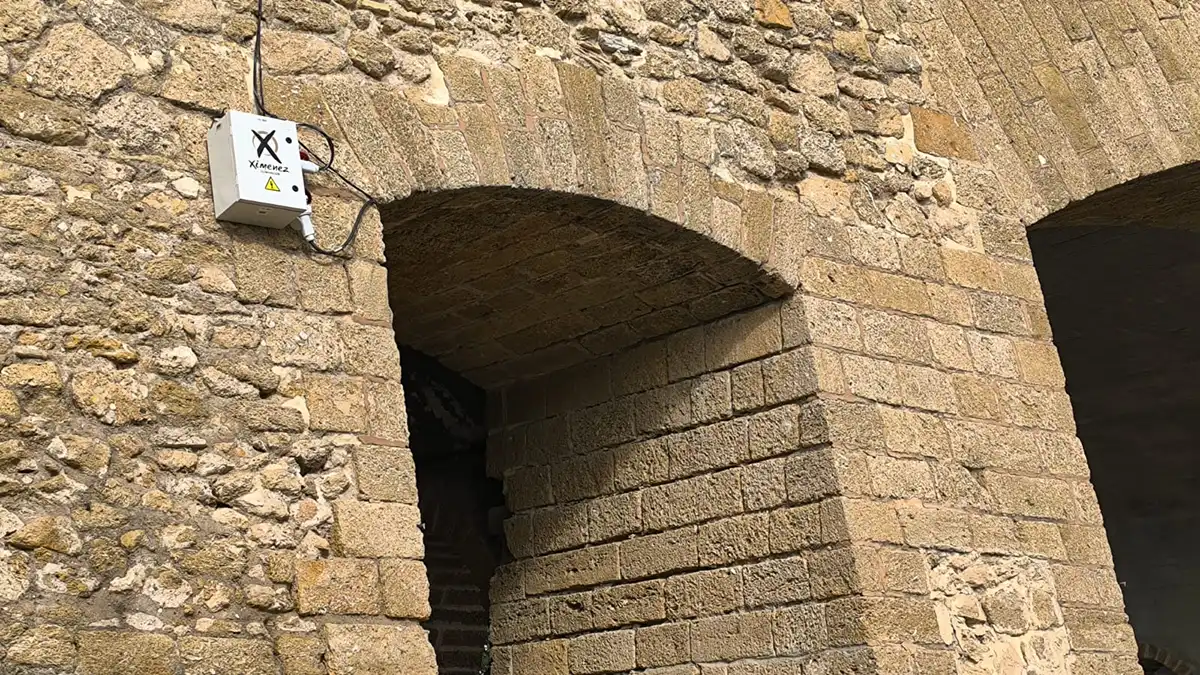 Un cuadro eléctrico con el nombre de la empresa de instalación del alumbrado extraordinario colocado directamente sobre la piedra ostionera de la Puerta de Tierra.