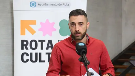 Delegado presentando la agenda cultural de Rota con camisa roja.