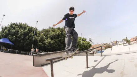 Chico con su monopatín bajando por la barandilla de una escalera.
