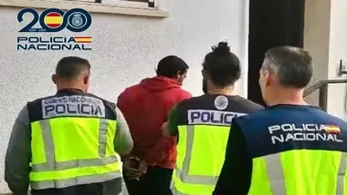 La Policía conduce al detenido al interior de comisaría, porta chaleco rojo.