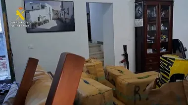 Fardos de droga y fusiles en una habitación.