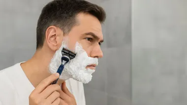 Hombre con la cara llena de espuma blanca de afeitar.