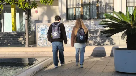 Dos jóvenes andando, chico y chica, con cazadoras de abrigo.
