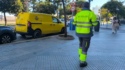 Una furgoneta de Correos aparcada en Cádiz mientras viandantes caminan por la acera
