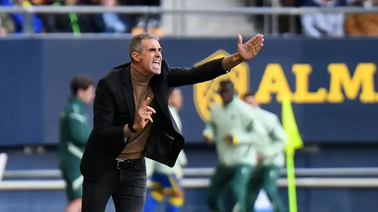 Imagen de Gaizka Garitano, entrenador del Cádiz CF, en la zona técnica del Nuevo Mirandilla. Aparece de pie junto a la línea de cal, gesticulando con el brazo derecho mientras da órdenes a sus jugadores. Viste ropa técnica del equipo y muestra un gesto serio y concentrado.