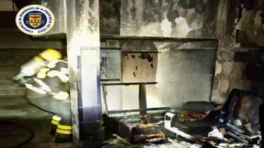 Bombero trabaja en el portal con restos carbonizados.