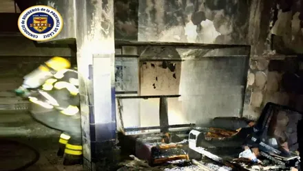 Bombero trabaja en el portal con restos carbonizados.