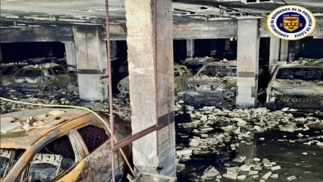 Coches quemados y agua en el garaje afectado por el incendio.