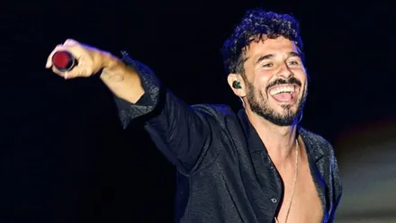 Antoñito Molina con camisa negra y micrófono en mano.