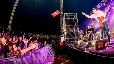 Cantante lanzando camisetas al público desde el escenario.