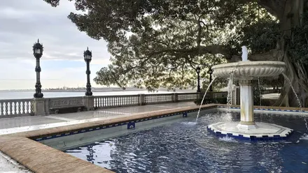 Nubes y claros en la Alameda de Cádiz, con una fuente en primer plano y el mar de fondo.