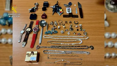 Mesa de madera con diferentes piezas de relojes y collares robados.
