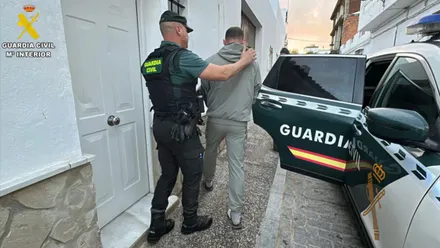 Agente de la Guardia Civil acompaña al detenido al coche.