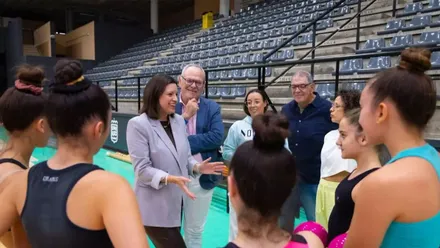 Patricia Cavada, con chaqueta gris con las chicas del equipo de gimnasia rítmica rodeándola.