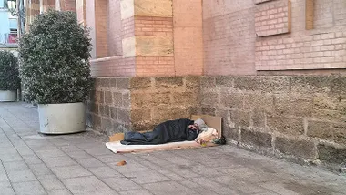 Una persona sin hogar duerme en la fachada principal del Gran Teatro Falla de Cádiz.