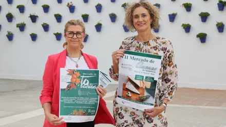 Dos mujeres con el cartel de las actividades de Rota en las manos.