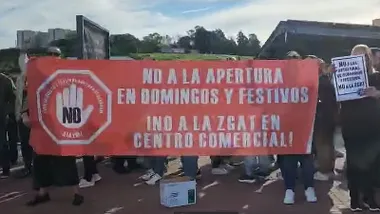 Manifestantes con pancarta roja y letras blancas por las aperturas de comercios los domingos y festivos.