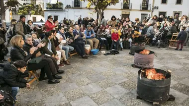 Personas reunidas en torno a la zambomba con bidones con candelas.