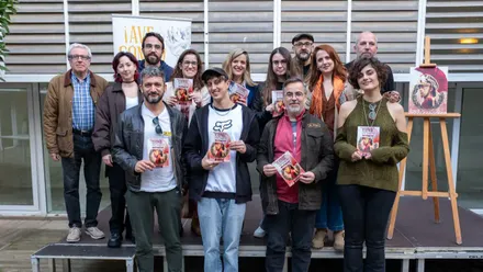 Parte del equipo de artistas junto a representantes del Ayuntamiento, con paneles del cómic expuestos en el ECCO y detalles visibles de las ilustraciones de la Gades romana..