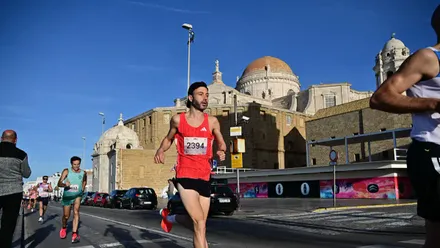 Corredores por el atraviesa la Campo del Sur junto a la Catedral de Cádiz durante la Media Maratón Ciudad de Cádiz, bajo un cielo despejado y soleado en la mañana del domingo.