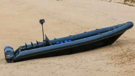 Narcolancha de color gris varada en la playa, en la orilla.