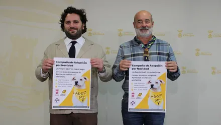 Responsables sostienen en las manos un cartel amarillo y blanco de la jornada de adopción de animales.