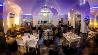 Salón de un bar en San Fernando con iluminación al techo en tono azulado.