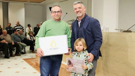 El alcalde de Rota entregando uno de los premios, posa con el premiado y con una niña rubia.