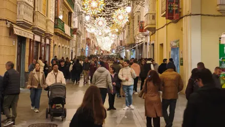 Vista nocturna de la calle Ancha de Cádiz iluminada con luces de Navidad, terrazas abiertas y personas paseando entre la decoración festiva.