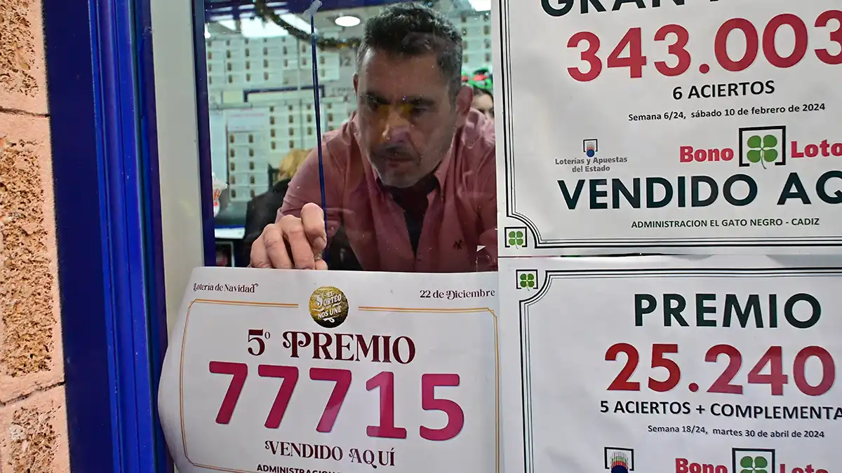 El lotero de 'El Gato Negro' coloca el cartel de uno de los quintos premios vendidos. Foto: Eulogio García.