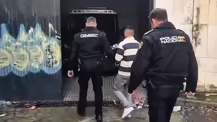 Dos policías nacionales llevan al detenido a comisaría.