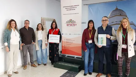 Francis Salado y otras personas posando en una habitación con la publicidad del proyecto Eracis+ en Chiclana.