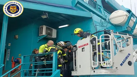 Ferry en color turquesa y bomberos evacuando al pasaje.